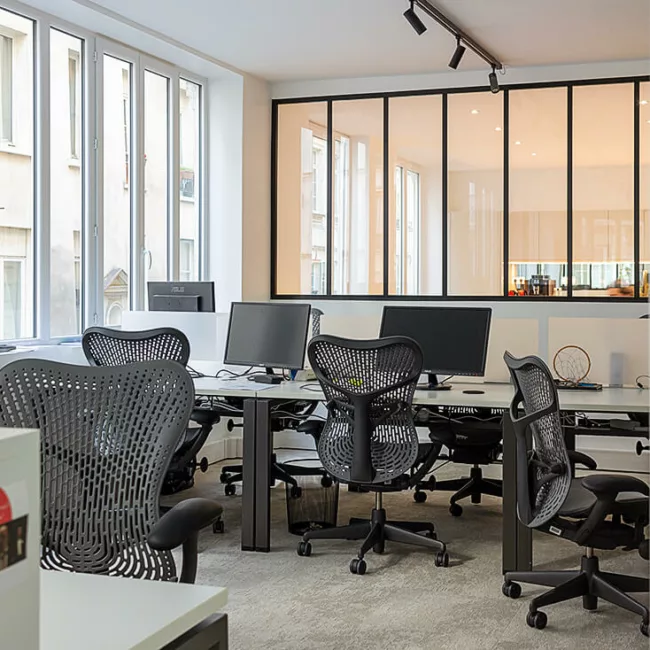 Espace de travail, quartier Sentier, flexible avec des bureaux modulables, des chaises ergonomiques, et des séparateurs amovibles, permettant différentes configurations pour le travail collaboratif ou individuel.