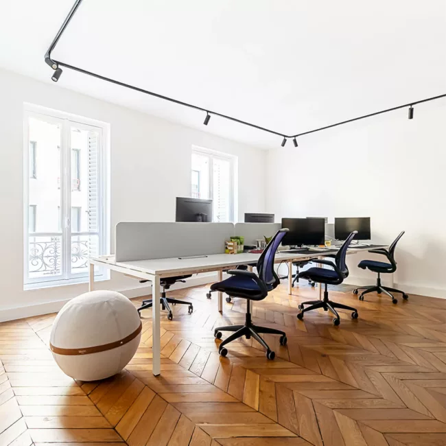 Espace de travail, quartier Archives, flexible avec des bureaux modulables, des chaises ergonomiques, et des séparateurs amovibles, permettant différentes configurations pour le travail collaboratif ou individuel.