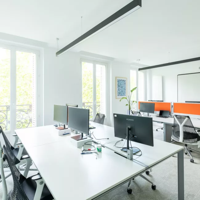 Espace de travail, quartier Réaumur-Sébastopol, flexible avec des bureaux modulables, des chaises ergonomiques, et des séparateurs amovibles, permettant différentes configurations pour le travail collaboratif ou individuel.