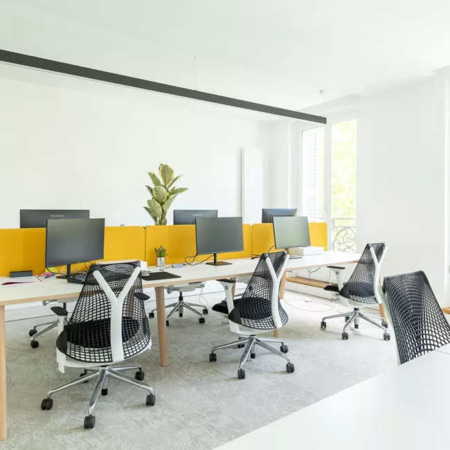 Espace de travail, quartier Réaumur-Sébastopol, flexible avec des bureaux modulables, des chaises ergonomiques, et des séparateurs amovibles, permettant différentes configurations pour le travail collaboratif ou individuel.