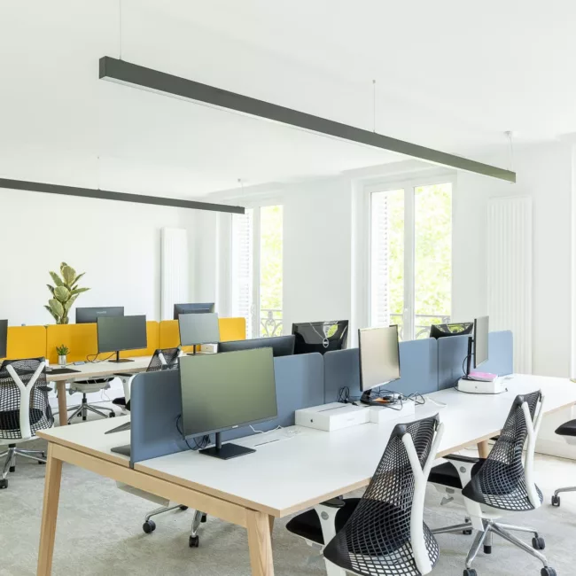 Espace de travail, quartier Réaumur-Sébastopol, flexible avec des bureaux modulables, des chaises ergonomiques, et des séparateurs amovibles, permettant différentes configurations pour le travail collaboratif ou individuel.