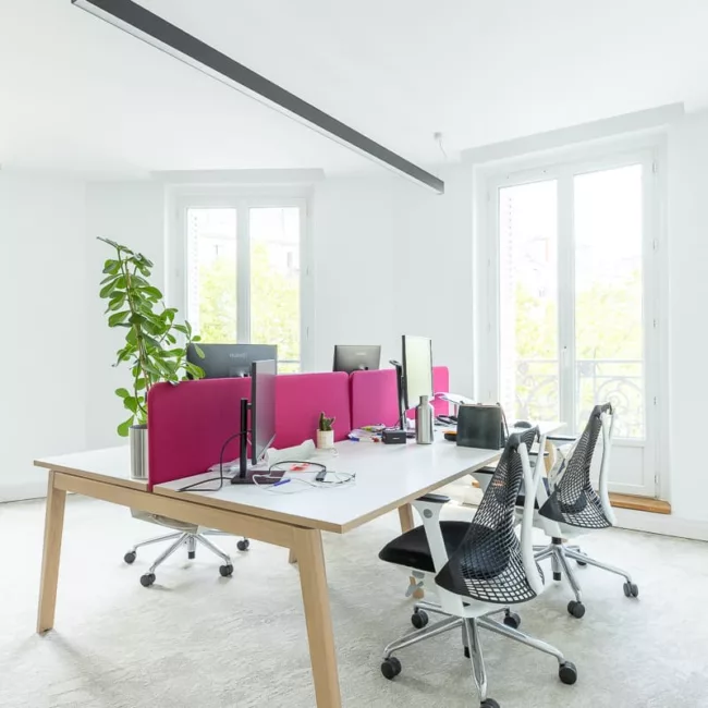 Espace de travail, quartier Réaumur-Sébastopol, flexible avec des bureaux modulables, des chaises ergonomiques, et des séparateurs amovibles, permettant différentes configurations pour le travail collaboratif ou individuel.