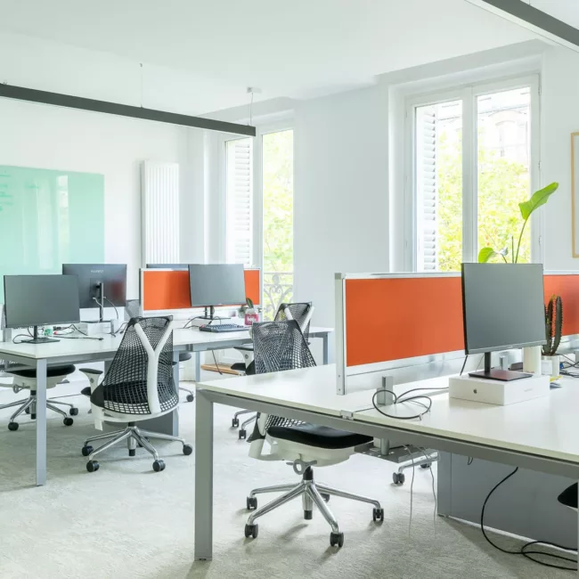 Espace de travail, quartier Réaumur-Sébastopol, flexible avec des bureaux modulables, des chaises ergonomiques, et des séparateurs amovibles, permettant différentes configurations pour le travail collaboratif ou individuel.