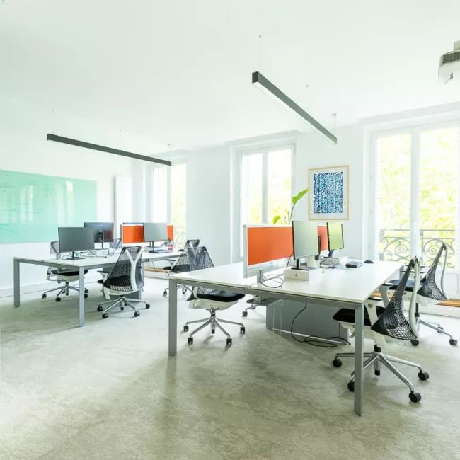 Espace de travail, quartier Réaumur-Sébastopol, flexible avec des bureaux modulables, des chaises ergonomiques, et des séparateurs amovibles, permettant différentes configurations pour le travail collaboratif ou individuel.