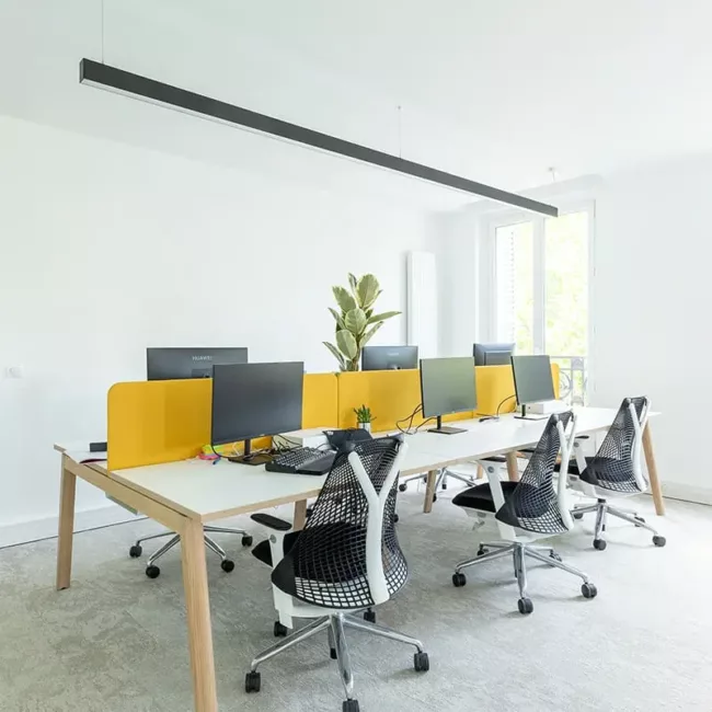 Espace de travail, quartier Réaumur-Sébastopol, flexible avec des bureaux modulables, des chaises ergonomiques, et des séparateurs amovibles, permettant différentes configurations pour le travail collaboratif ou individuel.