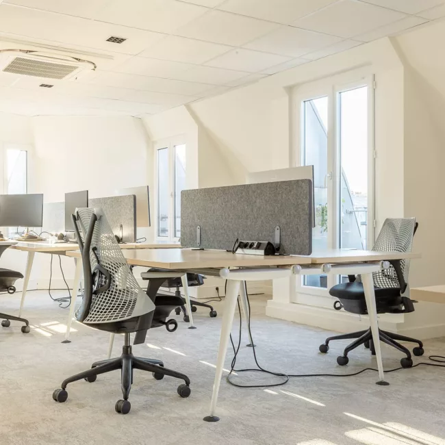 Espace de travail, quartier de l'Opéra, flexible avec des bureaux modulables, des chaises ergonomiques, et des séparateurs amovibles, permettant différentes configurations pour le travail collaboratif ou individuel.