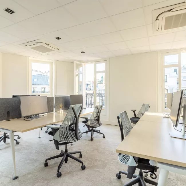 Espace de travail, quartier de l'Opéra, flexible avec des bureaux modulables, des chaises ergonomiques, et des séparateurs amovibles, permettant différentes configurations pour le travail collaboratif ou individuel.