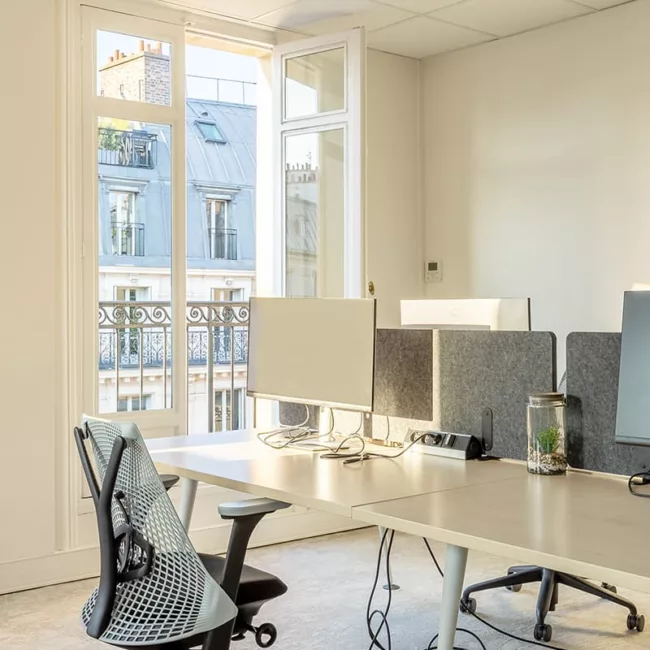 Espace de travail, quartier de l'Opéra, flexible avec des bureaux modulables, des chaises ergonomiques, et des séparateurs amovibles, permettant différentes configurations pour le travail collaboratif ou individuel.